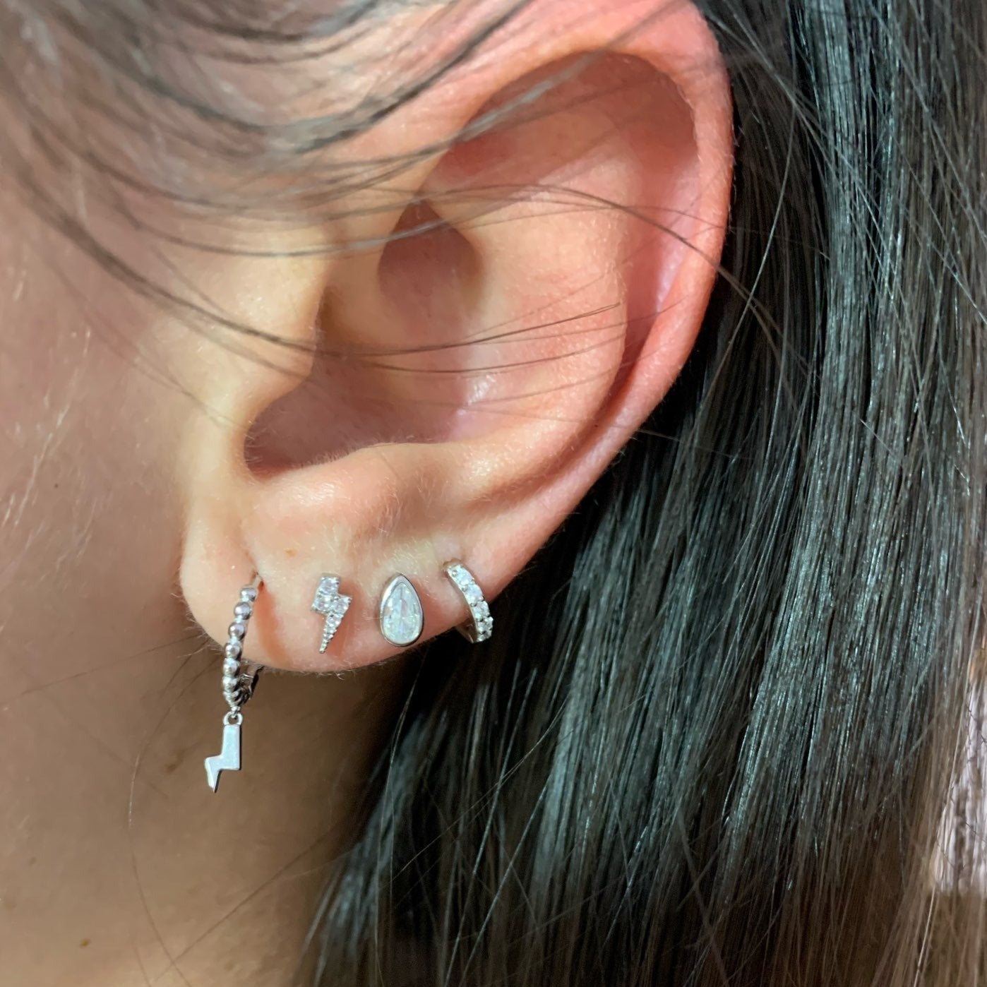 A model wearing silver lightning bolt earrings.