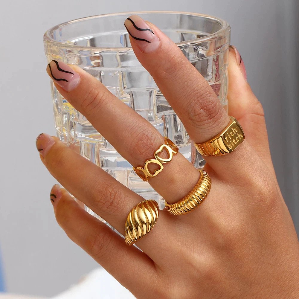 A woman wearing multiple chunky gold rings.