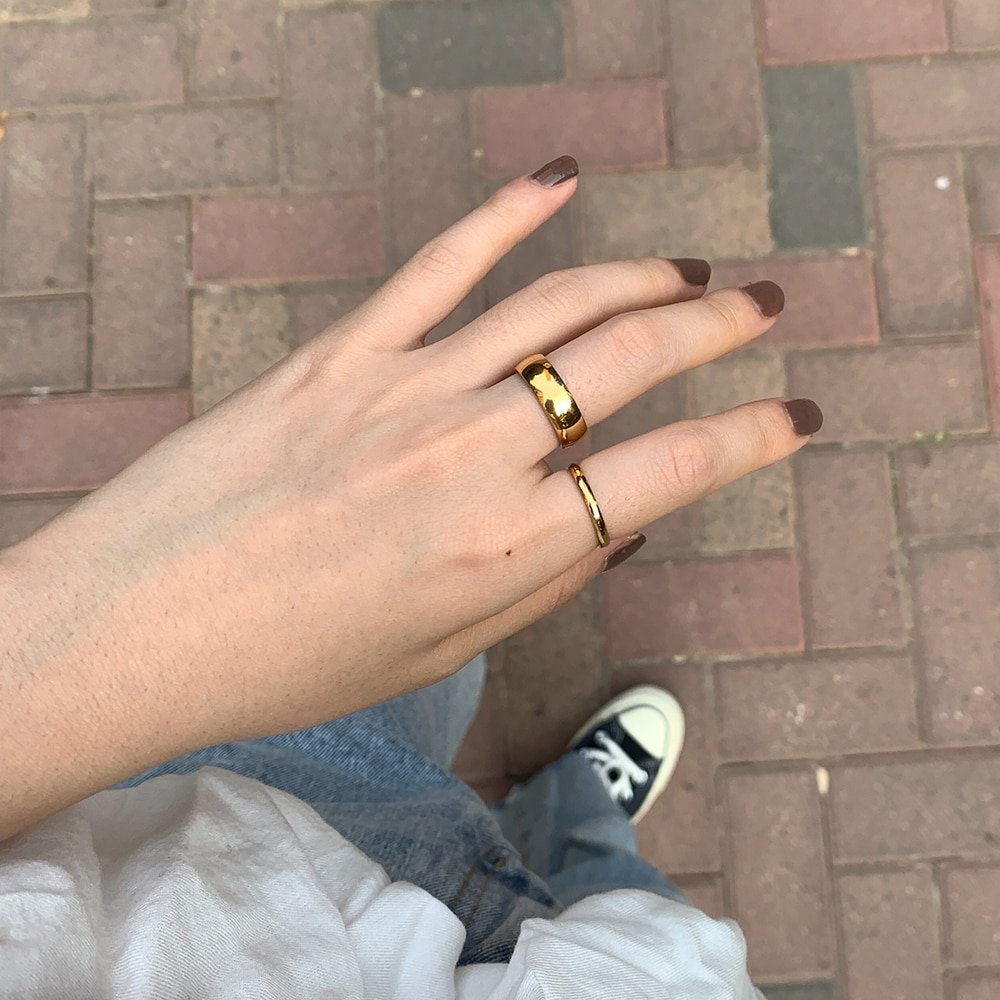 A woman wearing two gold ring bands.
