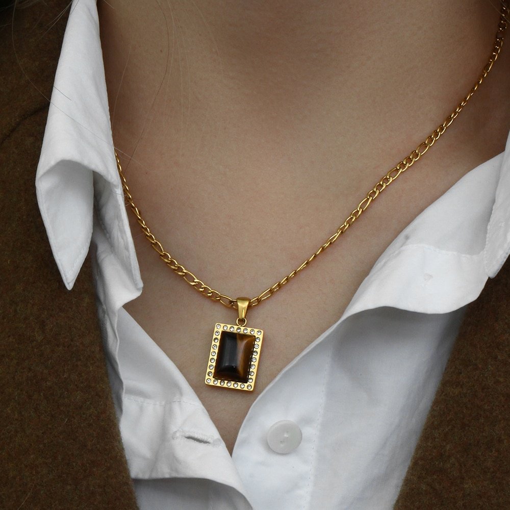 A woman wearing a gold rectangle tiger's eye necklace.