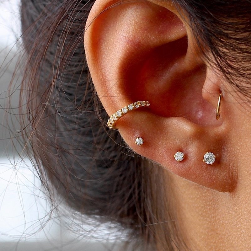 A model wearing three sizes of gold CZ stud earrings.