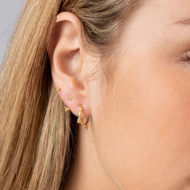 A model wearing gold stud earrings.