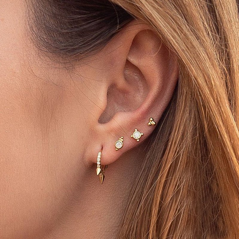 A model wearing multiple gold ear piercings.