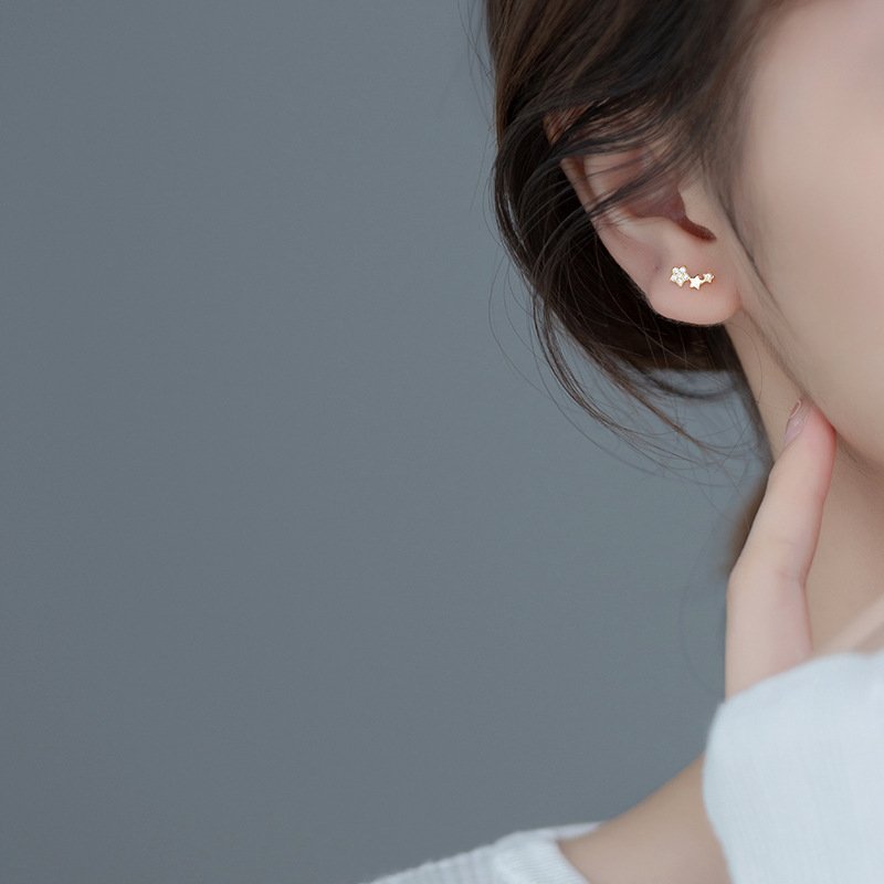 A model wearing the gold Triple Star Cartilage Stud.
