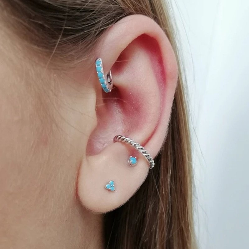 A model wearing multiple silver turquoise earrings.