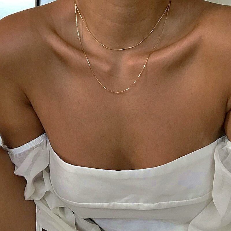 A model wearing two deliacte gold layering necklaces.