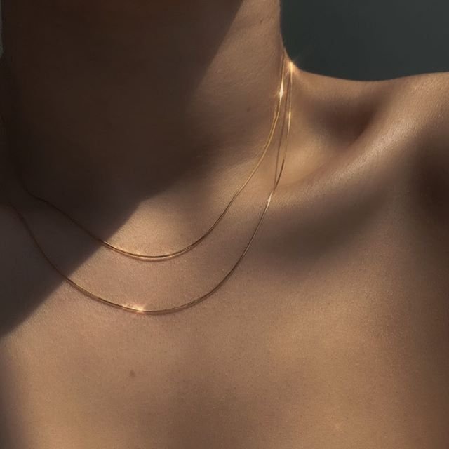 A model wearing two thin gold necklaces.