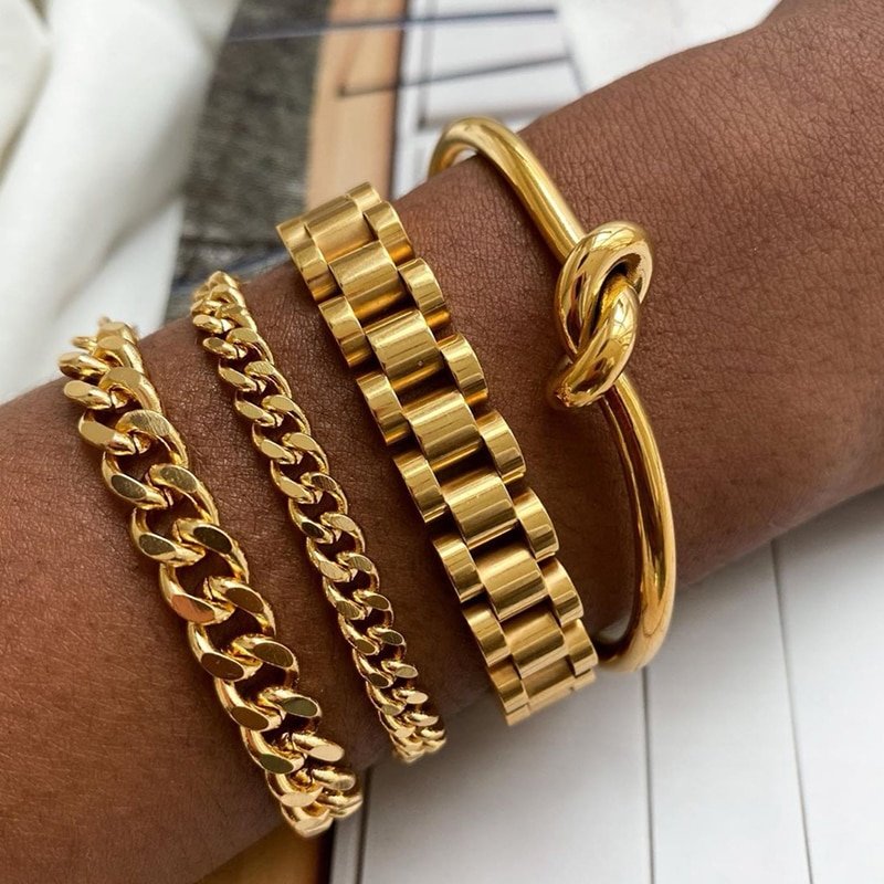 A model wearing multiple gold bracelets.