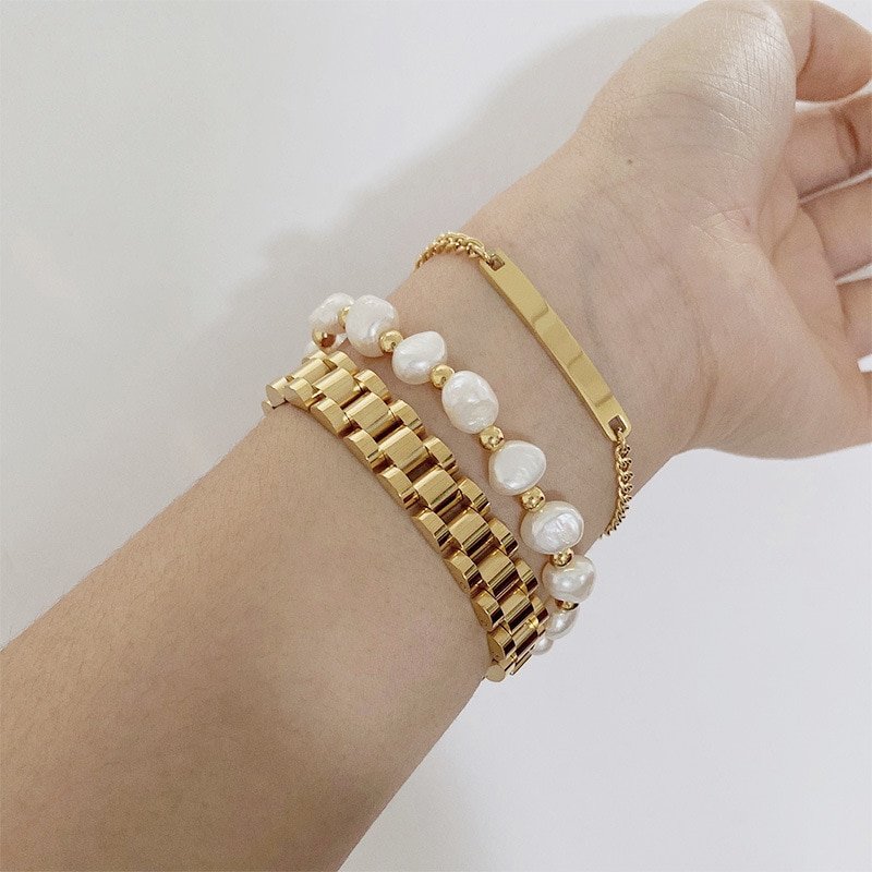 A model wearing three gold and pearl bracelets.