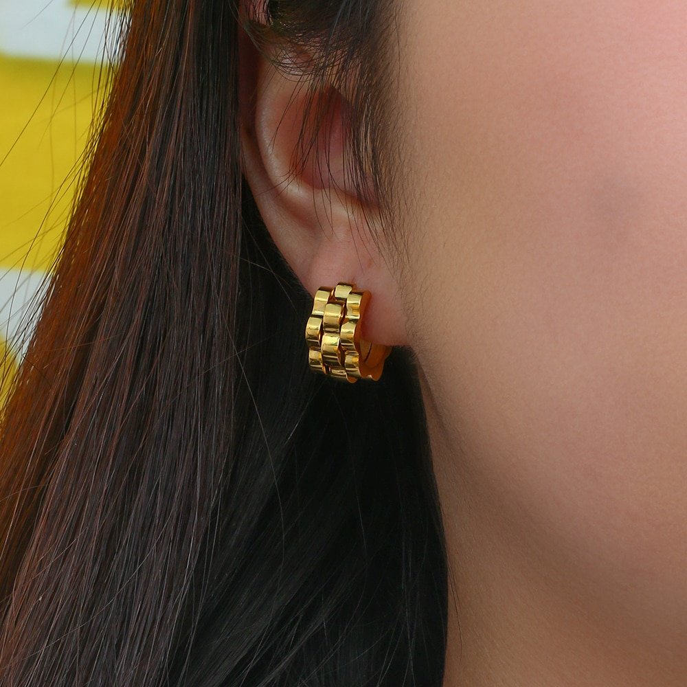 A model wearing chunky gold hoop earrings.