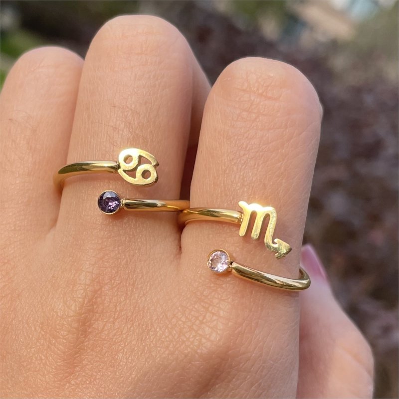 A woman wearing gold zodiac rings.